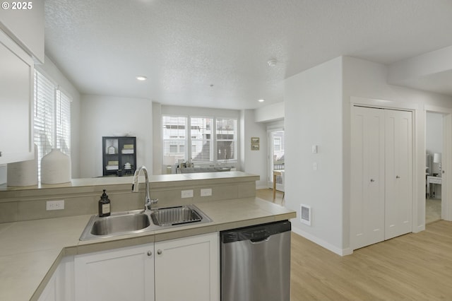 kitchen with light wood-style flooring, white cabinets, a sink, dishwasher, and a peninsula