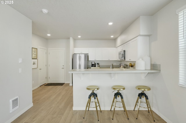 kitchen with appliances with stainless steel finishes, light countertops, and a breakfast bar area