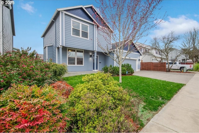 view of front of house with a front lawn, concrete driveway, fence, and a garage