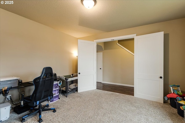 carpeted home office featuring a textured ceiling