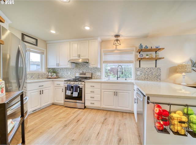 kitchen with white cabinetry, stainless steel appliances, backsplash, light hardwood / wood-style flooring, and sink