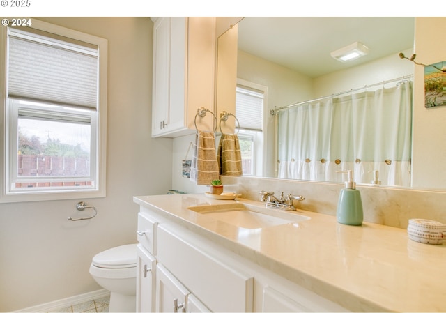 bathroom featuring toilet, vanity, and a healthy amount of sunlight