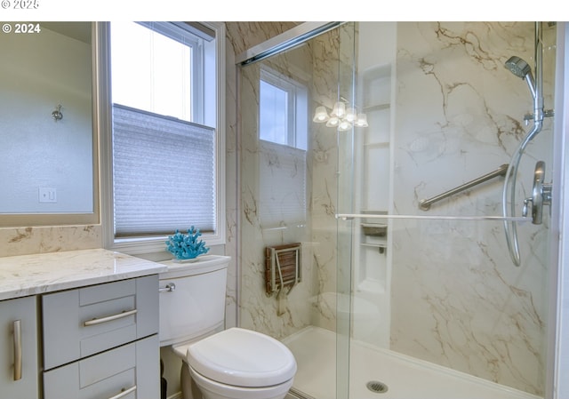 bathroom featuring toilet, vanity, and a shower with door