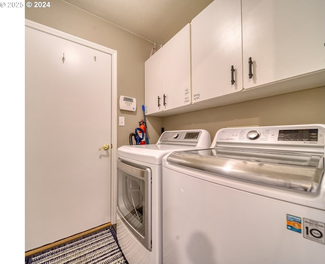 laundry room with washing machine and clothes dryer and cabinets