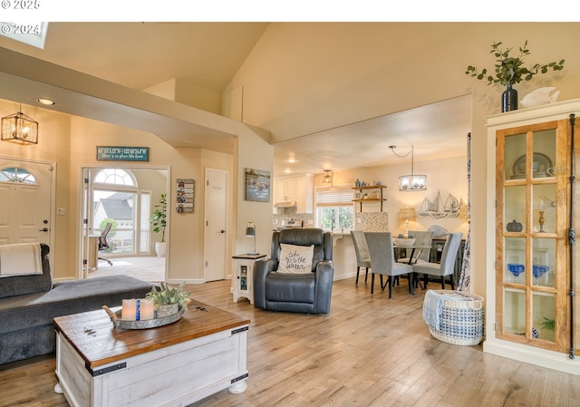 living room featuring vaulted ceiling, light hardwood / wood-style flooring, and a notable chandelier