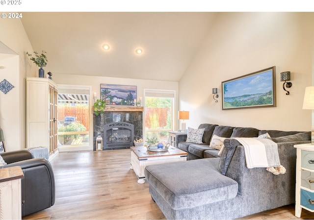 living room with vaulted ceiling, light hardwood / wood-style flooring, and a tile fireplace