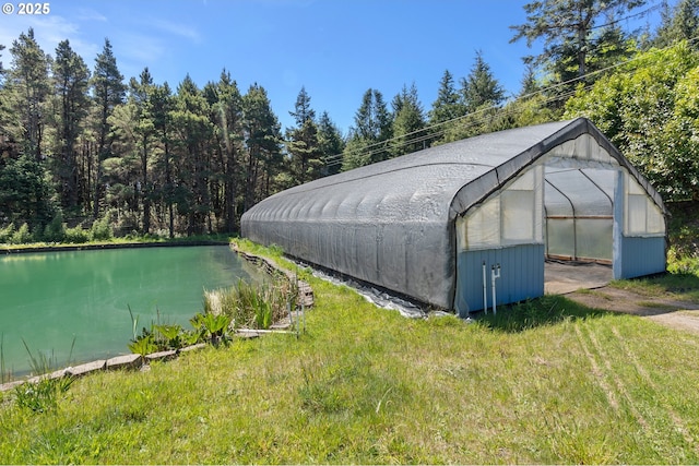 view of greenhouse with a yard and a water view