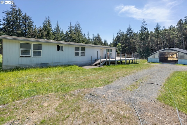 manufactured / mobile home with a carport, a wooden deck, and dirt driveway