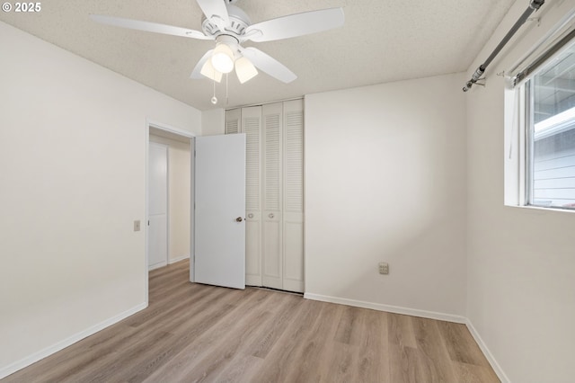 unfurnished bedroom with a textured ceiling, ceiling fan, wood finished floors, baseboards, and a closet