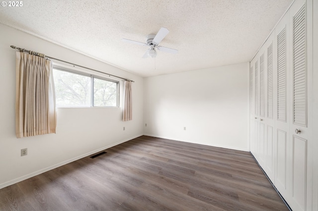 unfurnished bedroom featuring baseboards, visible vents, wood finished floors, a textured ceiling, and a closet