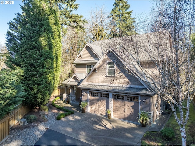 view of front of home featuring a garage, concrete driveway, roof with shingles, and fence