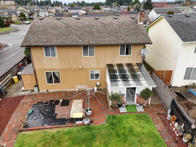 rear view of house featuring a shingled roof, a lawn, a chimney, fence, and a patio