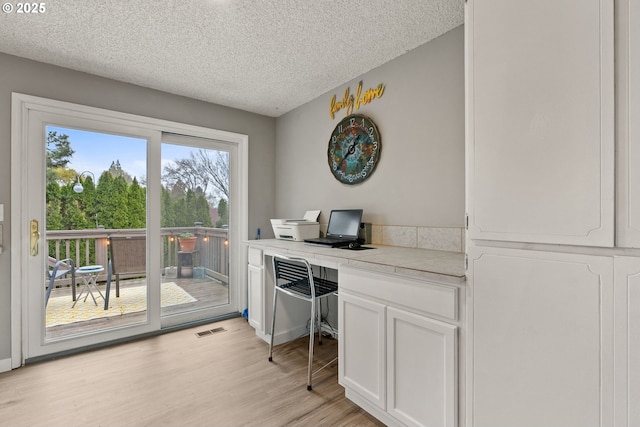 home office with visible vents, light wood-style floors, and a textured ceiling