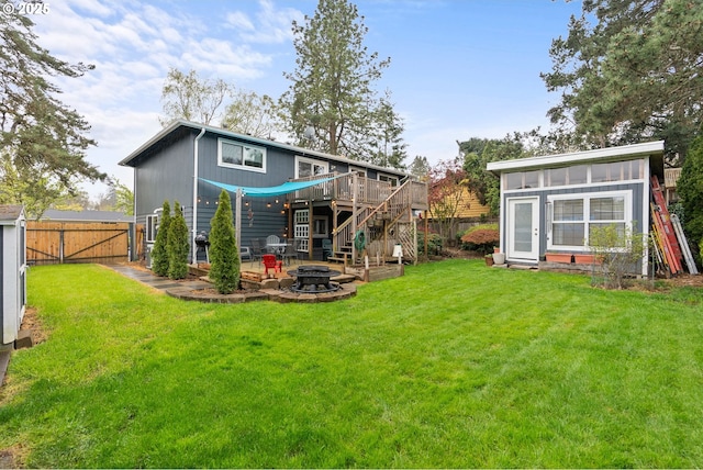 rear view of property featuring a yard, a fenced backyard, a fire pit, stairs, and a deck