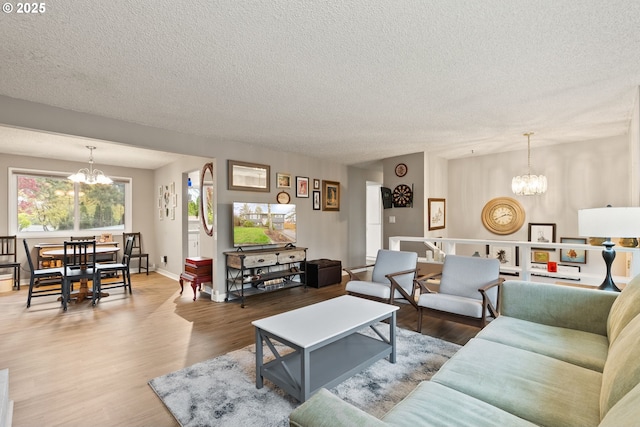 living area featuring a chandelier, a textured ceiling, baseboards, and wood finished floors