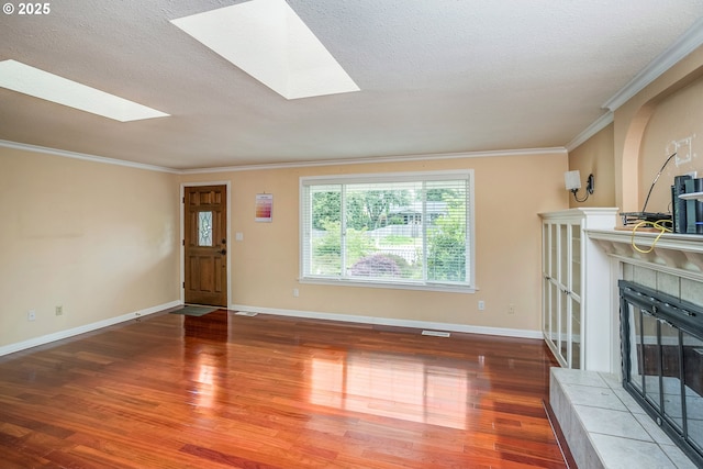 821 13th Ave, Seaside, OR 97138 - unfurnished living room with a tiled fireplace, wood finished floors, a skylight, ornamental molding, and a textured ceiling