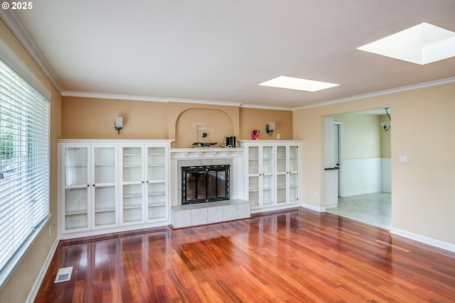 821 13th Ave, Seaside, OR 97138 - unfurnished living room featuring a skylight, wood finished floors, ornamental molding, and a tile fireplace