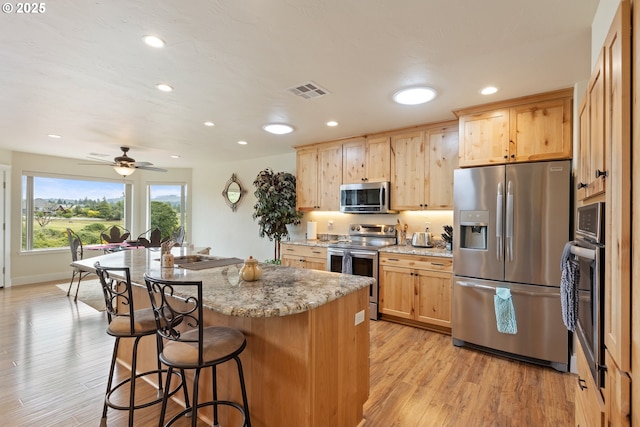 910 Swallow Ave, Sutherlin, OR 97479 - kitchen with stainless steel appliances, a breakfast bar area, a center island, recessed lighting, and light stone counters