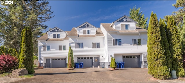 townhome / multi-family property with a shingled roof, an attached garage, and aphalt driveway