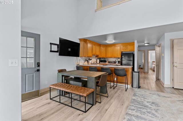 3979 NE Johns Ave, Neotsu, OR 97364 - kitchen with freestanding refrigerator, light wood-style flooring, stainless steel microwave, a towering ceiling, and a peninsula