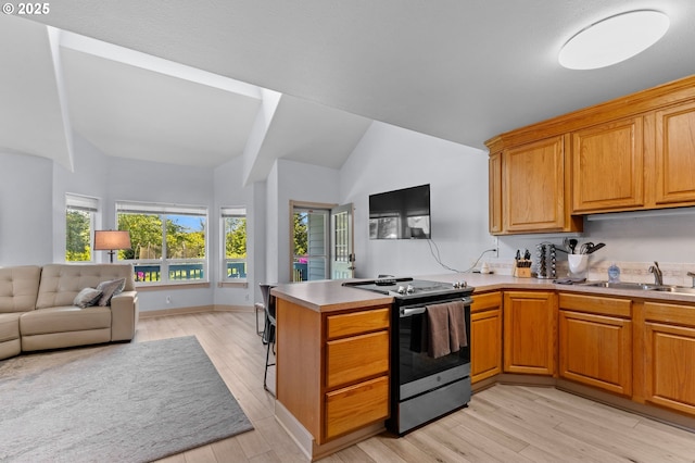 3979 NE Johns Ave, Neotsu, OR 97364 - kitchen featuring stainless steel electric range oven, a sink, a peninsula, open floor plan, and light wood-style flooring