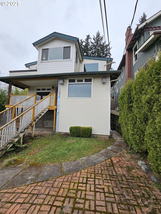 back of property with stairway and covered porch