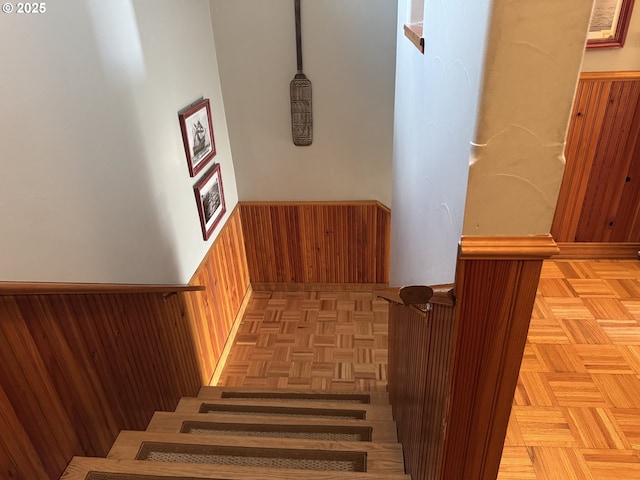 stairs with parquet floors and wood walls