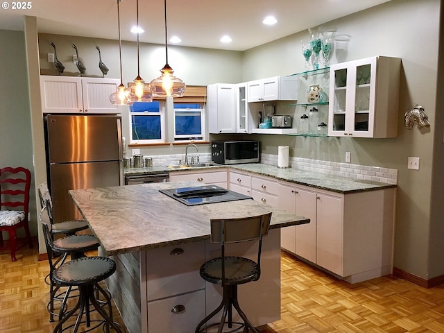 kitchen with stainless steel appliances, a kitchen bar, a kitchen island, and white cabinets