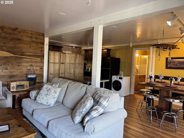 living room with washer / dryer, hardwood / wood-style floors, and wood walls