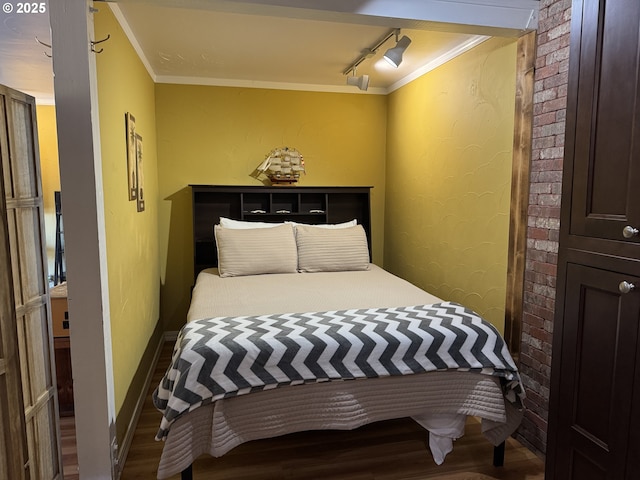 bedroom with crown molding, rail lighting, and hardwood / wood-style floors