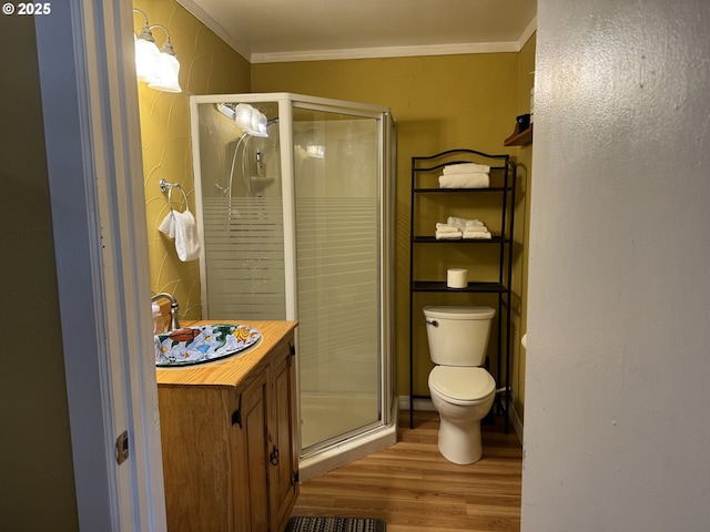 bathroom featuring hardwood / wood-style flooring, ornamental molding, toilet, and an enclosed shower