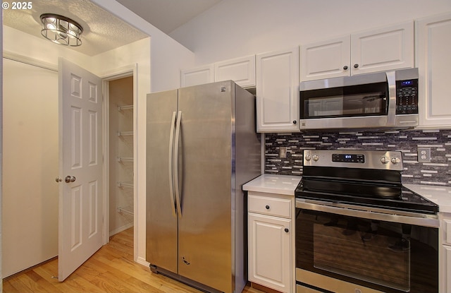 kitchen with white cabinetry, stainless steel appliances, light hardwood / wood-style flooring, and backsplash