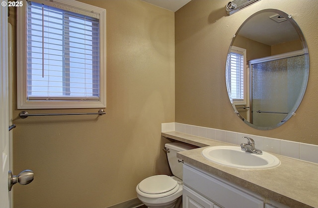 bathroom featuring vanity, an enclosed shower, and toilet