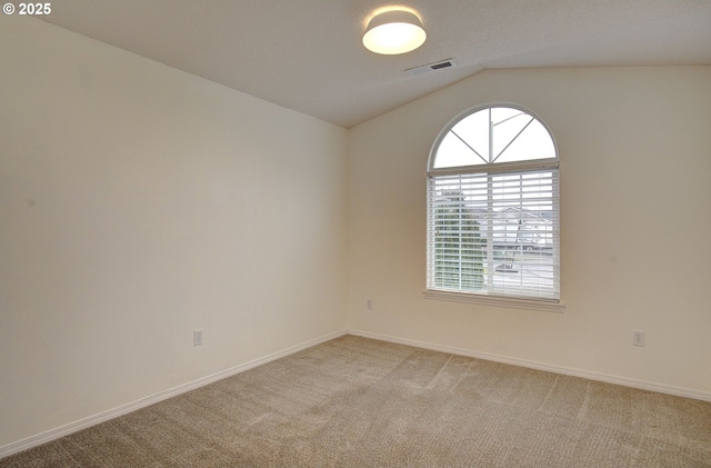 carpeted empty room with vaulted ceiling