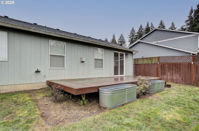 rear view of property with a wooden deck and a lawn