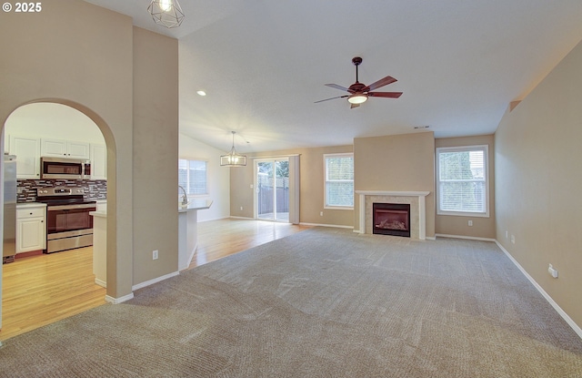 unfurnished living room featuring ceiling fan, lofted ceiling, and light carpet