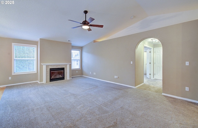 unfurnished living room featuring vaulted ceiling, light carpet, ceiling fan, and a fireplace