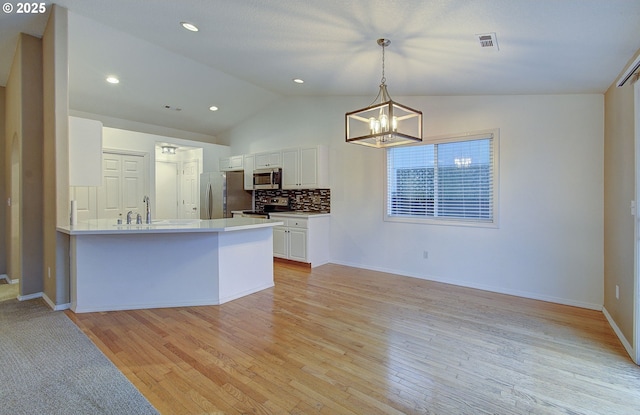 kitchen featuring stainless steel appliances, white cabinets, decorative light fixtures, kitchen peninsula, and light wood-type flooring