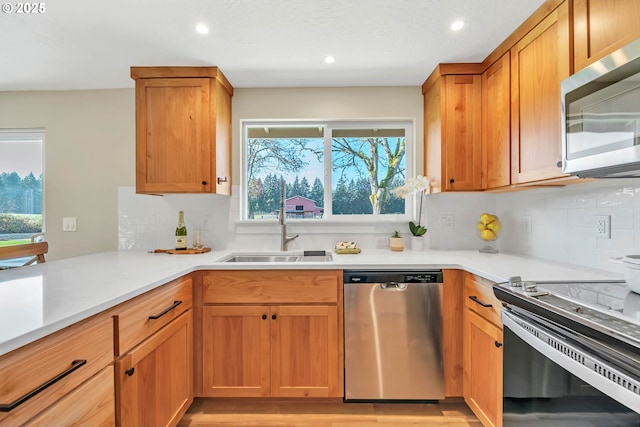 kitchen with tasteful backsplash, appliances with stainless steel finishes, light hardwood / wood-style floors, and sink