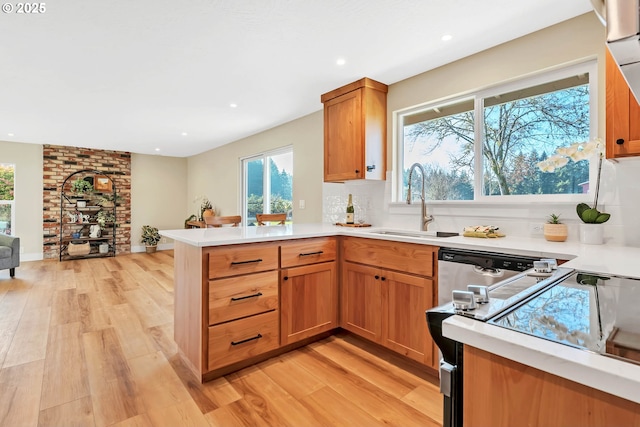 kitchen with kitchen peninsula, sink, light hardwood / wood-style flooring, and stove