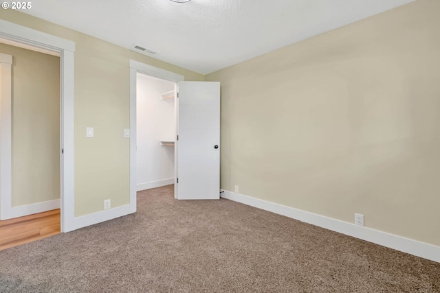 unfurnished bedroom featuring a closet, carpet flooring, and a spacious closet