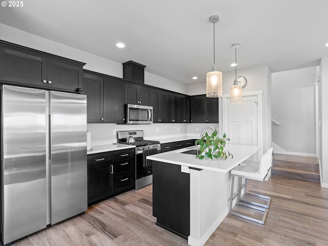 1793 SE Jonathan Ave, Dallas, OR 97338 - kitchen with appliances with stainless steel finishes, dark cabinets, light wood-style floors, light countertops, and a sink