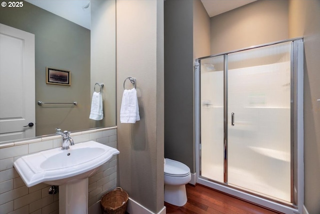 bathroom featuring a shower stall, toilet, and wood finished floors