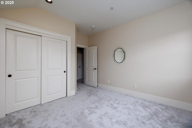 unfurnished bedroom featuring a closet, carpet flooring, baseboards, and vaulted ceiling