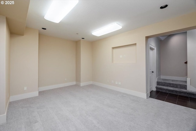 carpeted empty room with baseboards and stairway