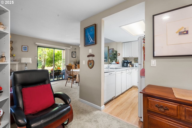living area featuring light carpet and baseboards