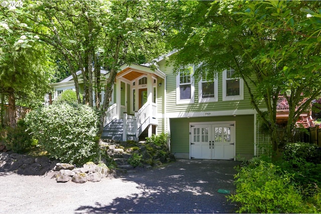 view of front facade with stairs, french doors, fence, asphalt driveway, and a garage