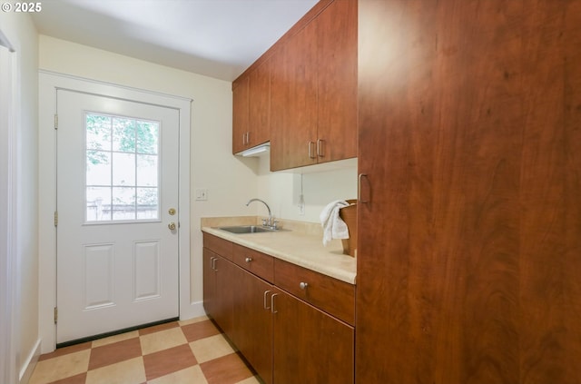 doorway to outside with a sink, light flooring, and baseboards