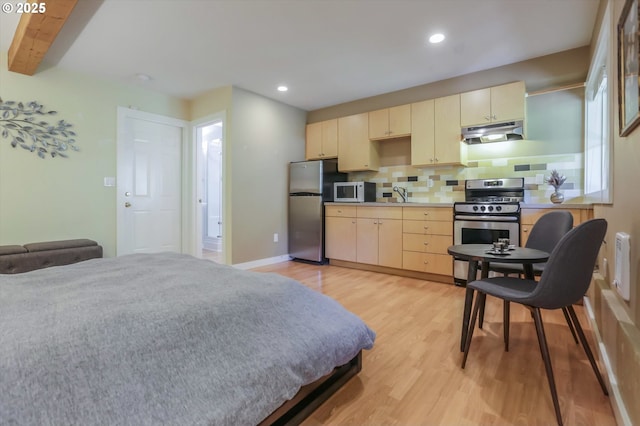 bedroom featuring freestanding refrigerator, a sink, light wood-style floors, recessed lighting, and beamed ceiling