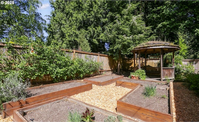 fenced backyard with a garden and a gazebo